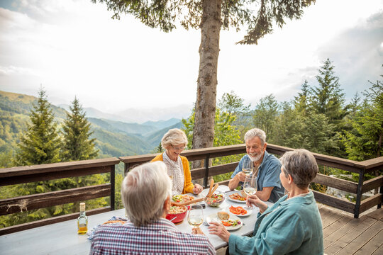 Senior friends dining with wine on mountain terrace