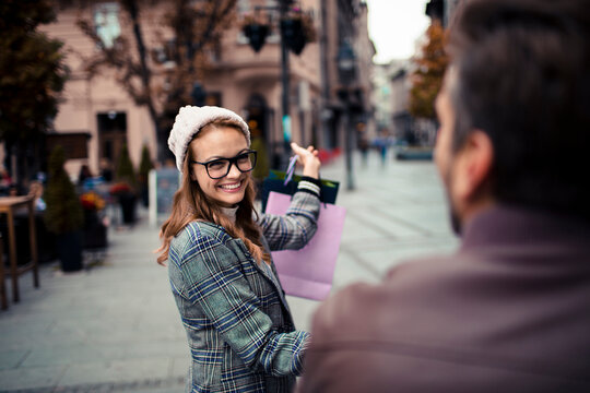 Smiling young woman with shopping bags on city street