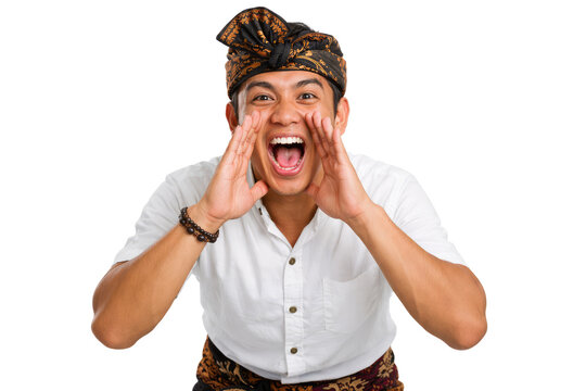 Traditional Balinese man shouting with hands around mouth, expressive Indonesian male in udeng headwear, cultural portrait of man screaming
