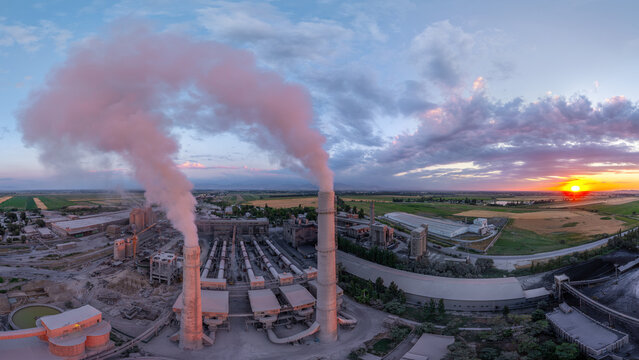 Aerial view of industrial cement plant at sunset with smokestacks
