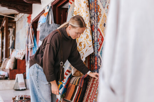 Female traveler shopping at a local market, browsing handmade goods and souvenirs, authentic travel experience, local culture, small business and destination shopping concept.