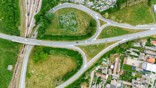 Aerial view of a highway interchange with cars driving through green fields and residential areas in Sabac, Vojvodina, Serbia.