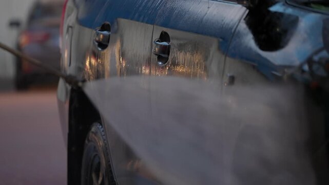 High pressure washer sprays water on a car. Car washing concept.