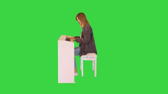 Aspiring young woman studies playing the electric piano on a Green Screen, Chroma Key.