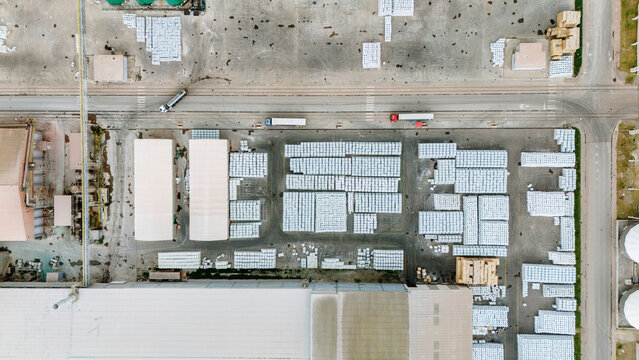 Aerial view of organized white pallets in an industrial warehouse yard with trucks and large factory buildings in Sabac, Vojvodina, Serbia.