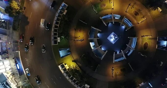 4K aerial top down night view of roundabout traffic at Plaza Agustin Gutierrez in Miraflores Lima Peru with smooth slow ascending drone movement