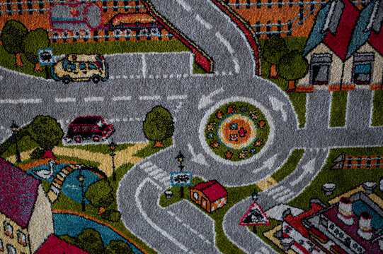 Close-up of a colorful tufted children&rsquo;s rug featuring a playful city and road design. Soft textured play mat background ideal for nursery, playroom, interior decor, and childhood concepts.