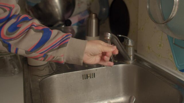 Practicing mindful hygiene with soap and water, Relaxing routine of washing hands at stainless steel sink, Calming act of cleansing hands in kitchen for personal wellbeing