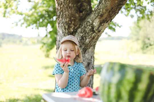 cute little girl eating watermelon outdoors in summertime. Child and watermelon in summer. 