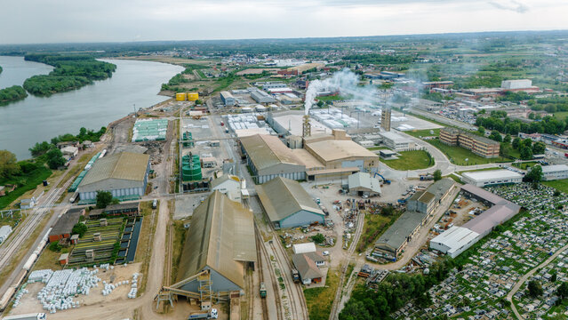 Aerial view of an industrial complex with large warehouses and smoking chimneys near the Sava River in Sabac, Vojvodina, Serbia.