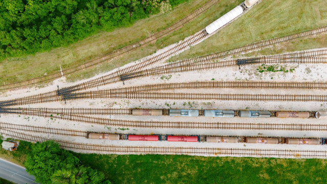 Aerial view of freight trains with tanker cars parked on multiple railway tracks surrounded by lush green trees and grassy fields Sabac, Vojvodina, Serbia.