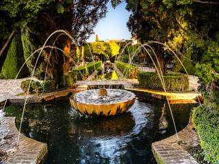 Obraz premium Ornate Stone Fountain in Alhambra Generalife Gardens With Arched Water Jets at Sunset, Granada