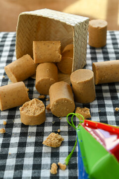 Traditional Brazilian peanut candy known as pacoca de rolha scattered on a black and white checkered tablecloth next to a wicker basket, perfect for Festa Junina or June festival celebrations