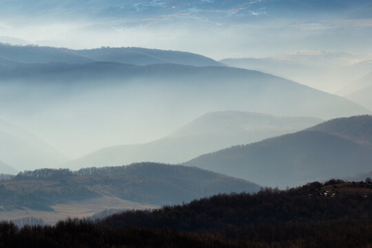 Layered mountain landscape with mist and soft light creating atmospheric depth