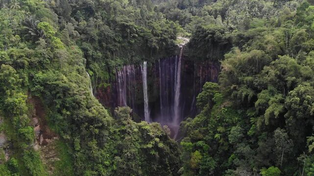 Drone Flying Above Forest Towards Tumpak Sewu Waterfall Panning Down to Reveal Falls, Java, Indonesia