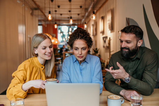 Business colleagues collaborating on laptop in coffee shop