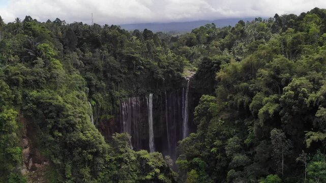 Drone Flying Above Forest Towards Tumpak Sewu Waterfall Panning Down to Reveal Falls, Java, Indonesia
