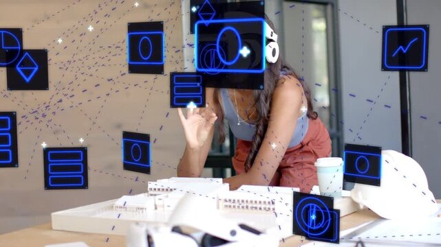 Female architect reaching over table and moving blue AR panels, adjusting headset, reviewing models