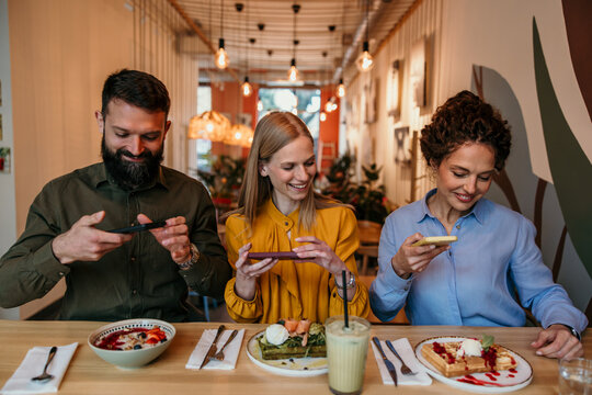 Friends taking food photos at cafe for social media