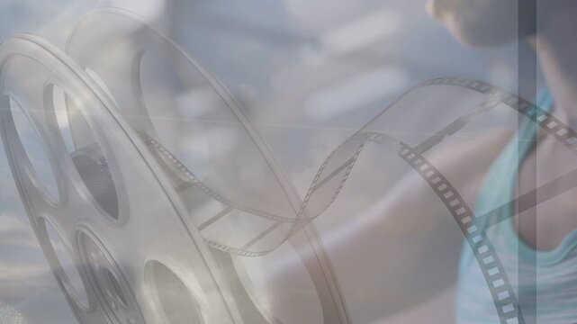 Woman reaching, manipulating reel to adjust film for playback with filmstrip overlaying reel
