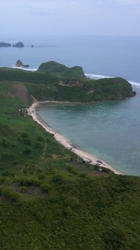 Aerial Green Island Cape With Curved Beaches, Rolling Hills And Farmland Pockets, Long Reef Line Shaping Waves, Secluded Bays, Turquoise Shallow Water Meeting Deep Ocean, Katil beach,Lombok,Indonesia