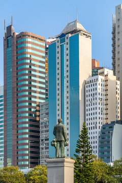 The bronze statue of Sir James Kotewall stands before a backdrop of modern glass office towers in the Central district of Hong Kong, Hong Kong.