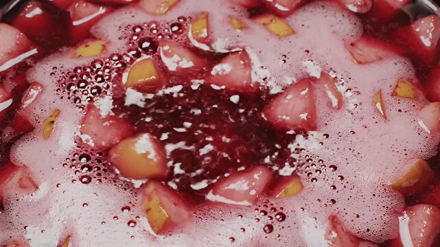 Sliced fruit simmering in red mulled wine with froth