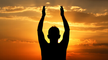 Fototapeta premium Silhouette of a person with arms raised against a sunset sky