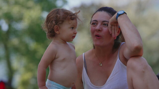 Mother kissing toddler on cheek during summer picnic, warm and affectionate outdoor family moment filled with love, tenderness, and emotional bonding