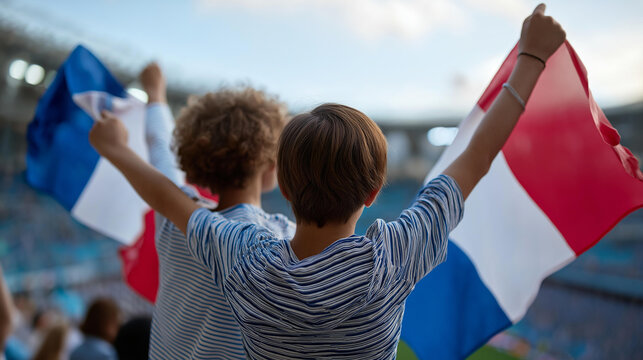 Rear view of young fans in a stadium waving national flags during an international football match, world cup supporter concept, patriotic crowd, global sports event, defocused