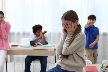 Fototapeta premium Girl getting bullied by her classmates in classroom, selective focus