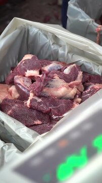 Close up of meat portions being placed into crates in slaughterhouse, organized distribution and sharing workflow, food preparation process for community supply, vertical format industrial footage.
