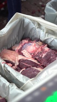 Close up of meat portions being placed into crates in slaughterhouse, organized distribution and sharing workflow, food preparation process for community supply, vertical format industrial footage.