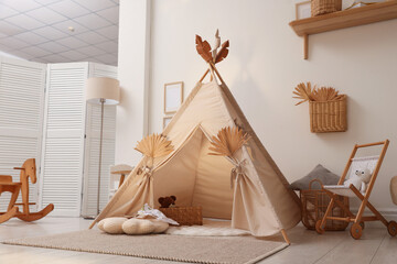 Stylish wigwam with dry leaves in child's room © New Africa