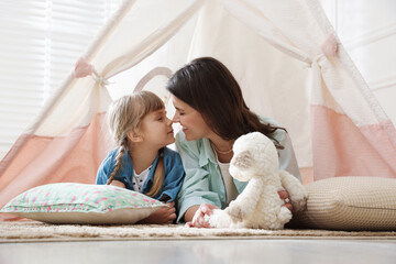 Mother and her daughter with toy near wigwam at home © New Africa