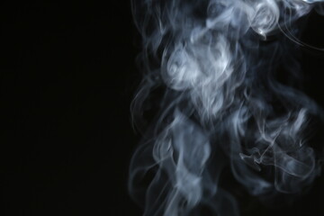 Obraz premium A white curved texture, magical smoke from an incense stick rising from the surface against a dark black background with copy space. Mystical pattern, concept of meditation and relaxation. Magical fog