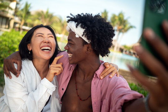 Diverse content creator couple vlogging or streaming from a scenic tropical beach on summer vacation