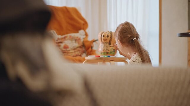 Young girl at play table arranging pumpkin pie, pretend baking tea party with doll and orange blanket, sunlit window, warm cinematic home interior, slow intimate moment, delicate hands shaping pastry,