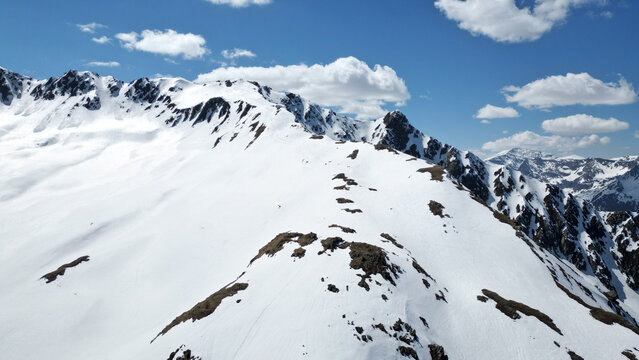 Aerial view of the snow-covered Pointe Ronde mountain ridge with rocky outcrops under a blue sky with white clouds Trient, Valais, Switzerland.