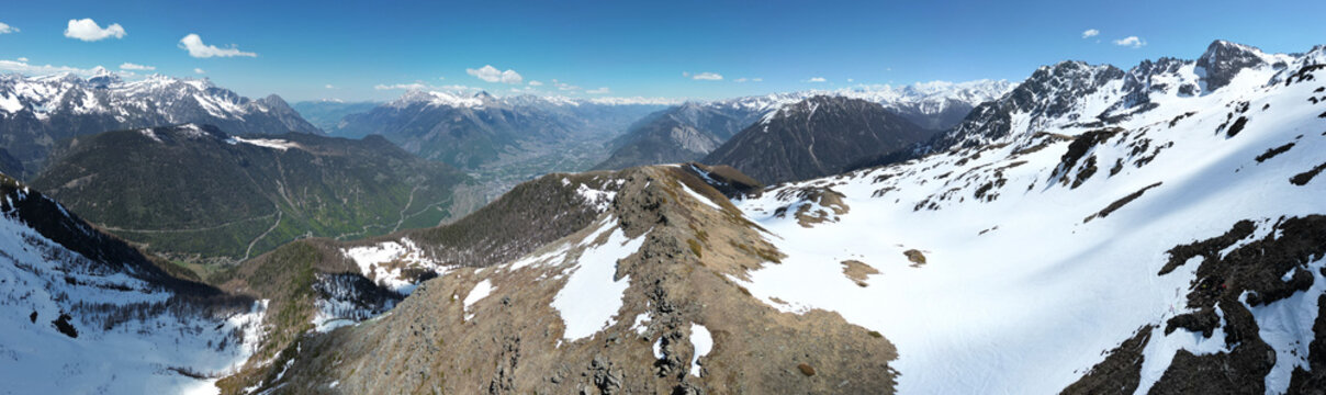 Aerial view of Pointe Ronde mountain peak with snow-covered slopes, rocky ridges, and the distant Trient valley under a clear blue sky Trient, Valais, Switzerland.