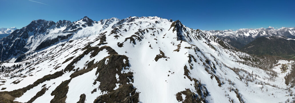 Aerial view of Pointe Ronde mountain peak with snow-covered slopes and rocky ridges under a clear blue sky in Trient, Valais, Switzerland.