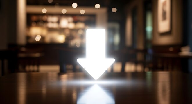 Bright white downward arrow icon on a wooden table in a blurred cafe interior direction symbol