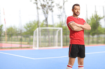 Fototapeta premium Football player in a red jersey standing with his arms crossed