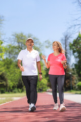 Fototapeta premium Elderly man and woman in sportswear walking in a park