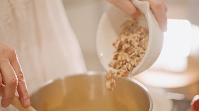 Pouring chopped pecans into warm filling, wooden spoon guiding nuts into metal bowl, closeup hands, crunchy topping prep, natural light, rustic kitchen scene, pastry maker finishing pumpkin pie layer