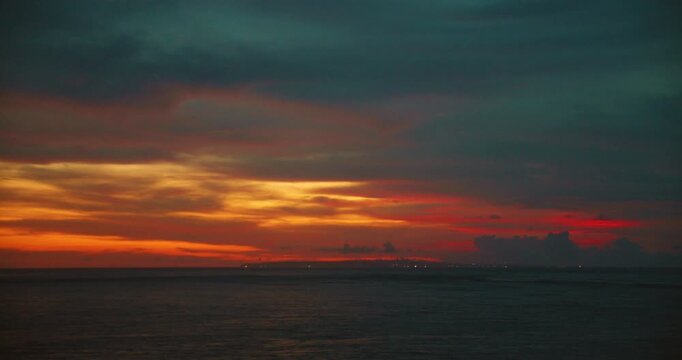 Colorful dramatic sunset sky with dark clouds and last light over tranquil ocean water horizon