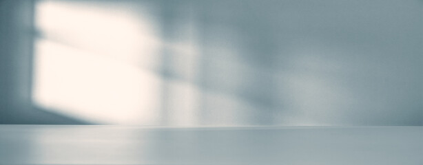 Banner of Minimalist empty room with soft natural light casting shadow on a wall. Clean, modern interior space for product presentation, with a beam of light falling into the room through the window © Pihuliak