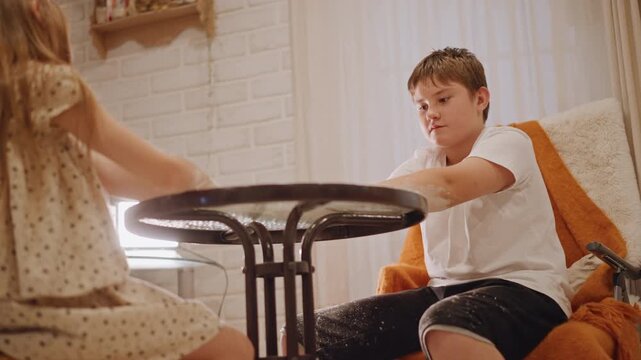 White boy and girl at small table making pumpkin pie, flour sprinkle and giggles, polka dress sister reaching across, soft sunlight, orange throw on chair, shared hands shaping dough, warm domestic