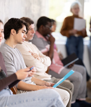 People of different ages sit together in line waiting for an interview at a prestigious company. After the dismissals, men and women came to apply for a vacancy