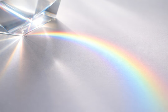 Prism creating a colorful rainbow on white surface